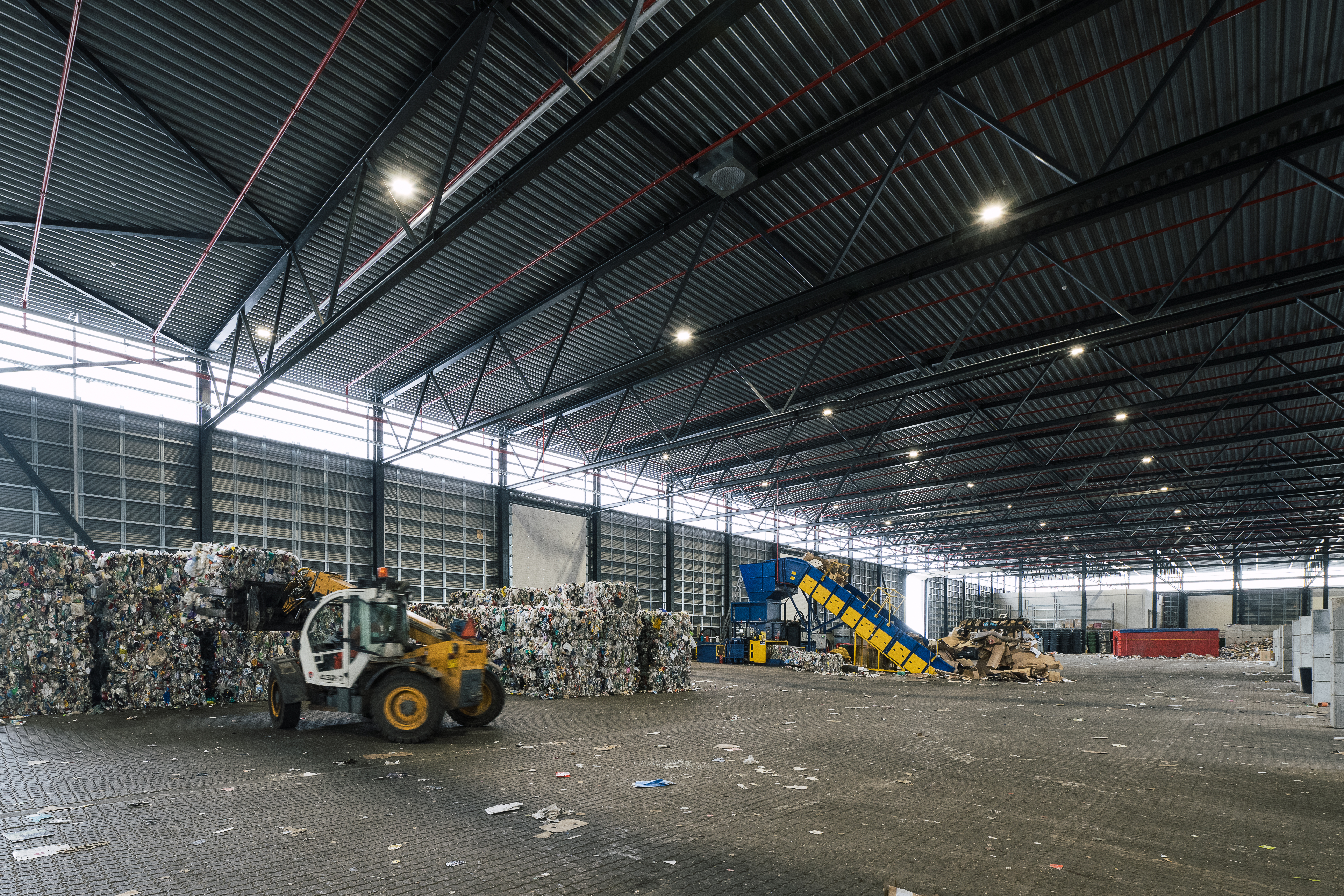 Indvendig hal med affaldshåndtering på RessourceCenter Vejle. Stor industrihal med maskiner og affald i forskellige fraktioner.