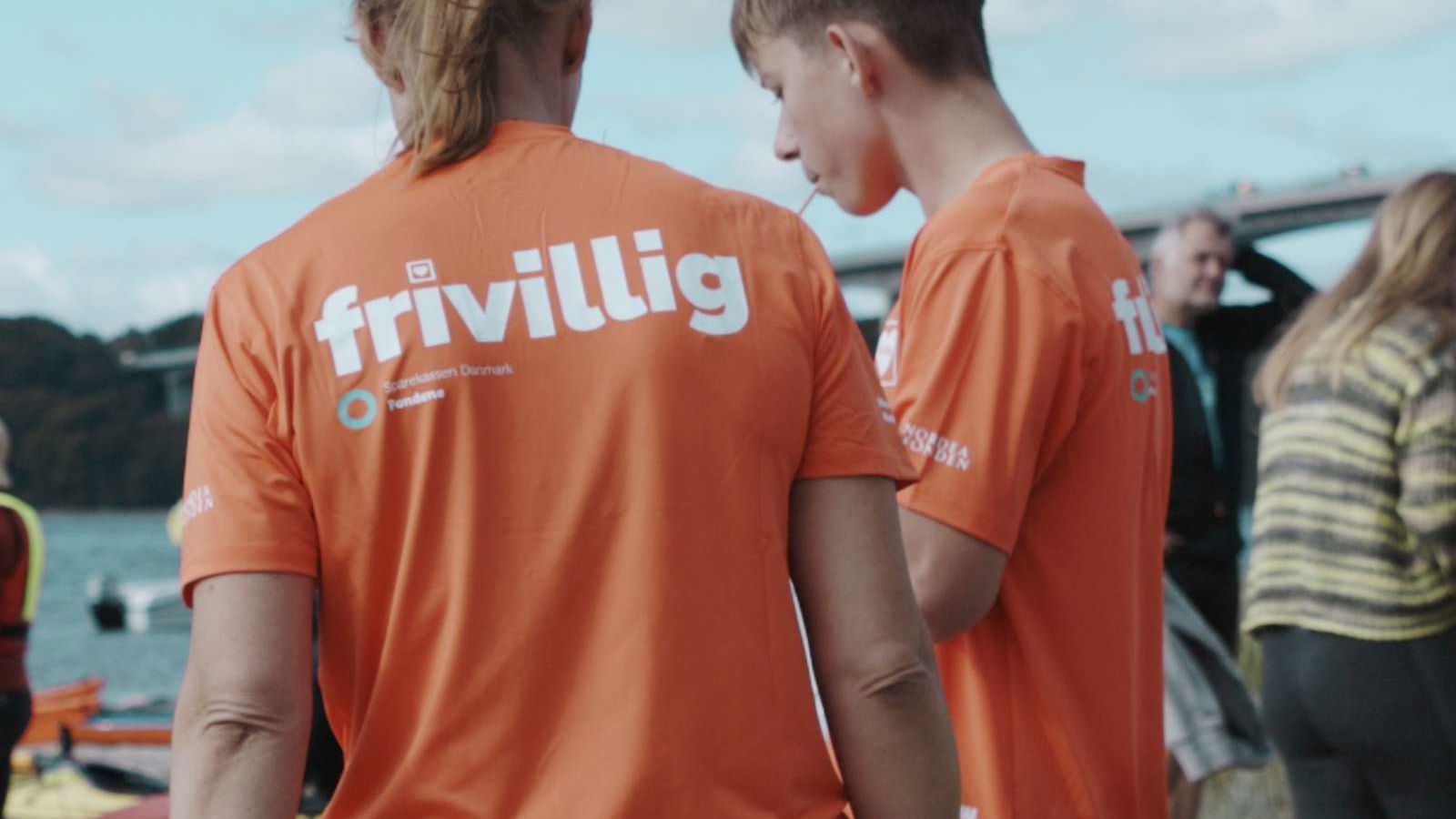To frivillige unge mennesker iklædt orange t-shirt påtrykt Frivillig